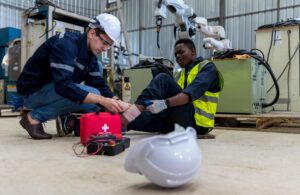 warehouse worker receiving emergency first aid from coworker after injuring self using machinery